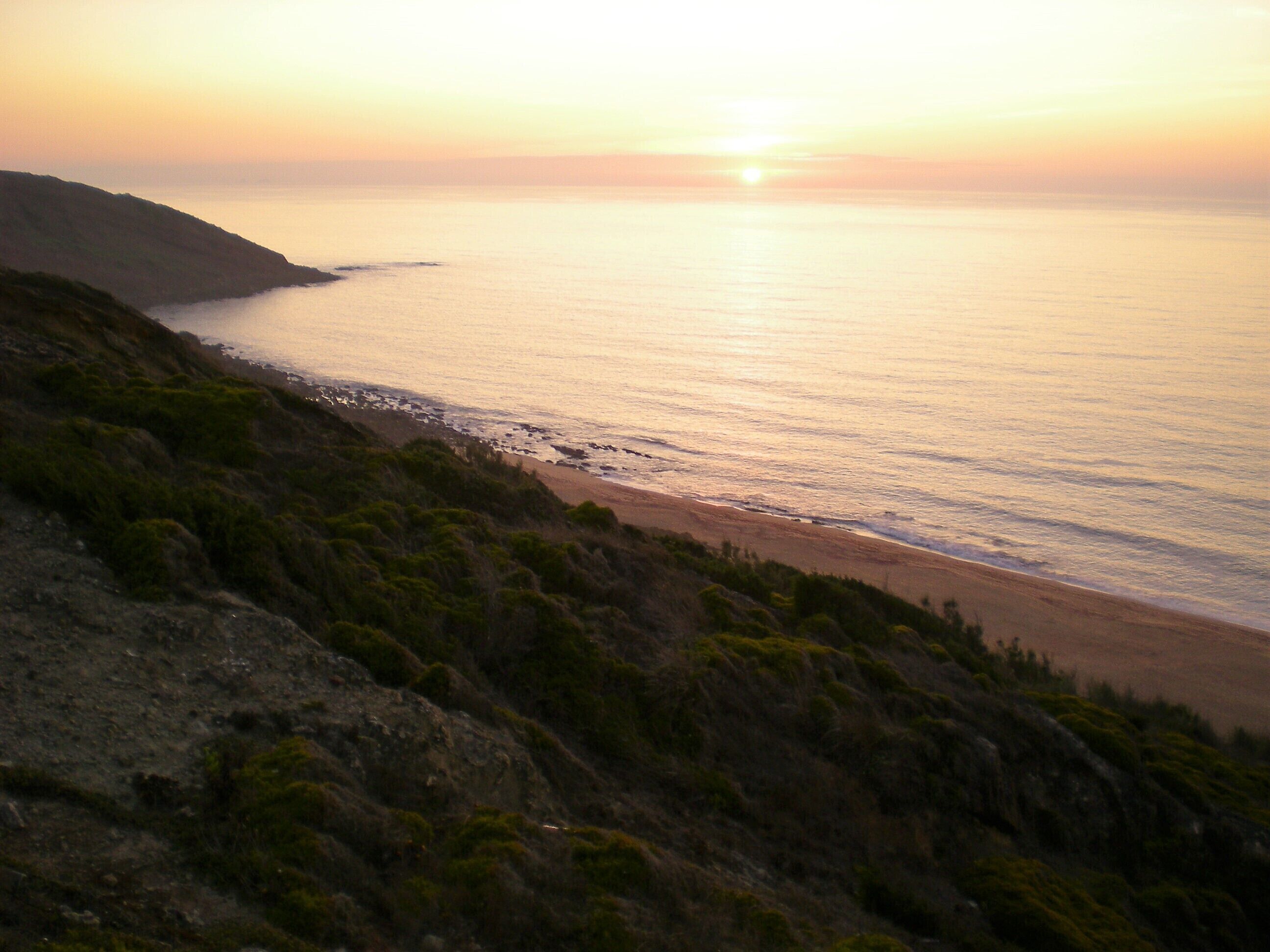 A coastal landscape with a beach and rocky terrain.