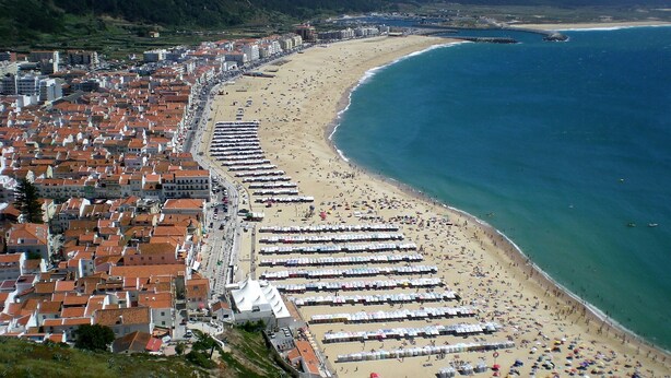 A coastal city with a long beach lined with rows of beach umbrellas and sun loungers. - Country and  beach, the best of both worlds. (Famalicão da Nazaré)