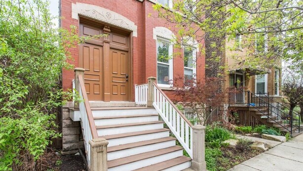 A two-story brick building with a wooden front door and white-painted steps leading to a porch. - iKlektik House Chicago (Chicago)