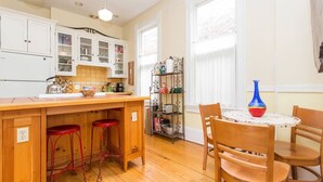 A kitchen with wooden cabinets, a central island with stools, and a dining table with chairs. - iKlektik House Chicago (Chicago)