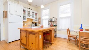 A kitchen with wooden cabinets, a central island, and a dining area with chairs and a table. - iKlektik House Chicago (Chicago)