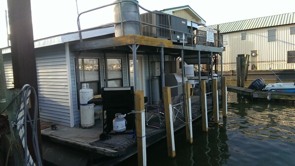 A houseboat with a small deck, a gas cylinder, and a Yamaha outboard motor.