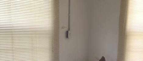 Una habitación pequeña con cama individual, ventana en una pared y toma de corriente en la pared.