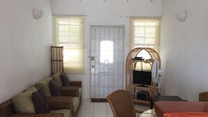 Un salón amplio con ventilador de techo, muebles de mimbre y suelo de baldosas.