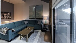 A modern living room with a sectional sofa, a wooden coffee table, and a glass door leading to a balcony. - True Ski in Ski Out in Old Town. Newly Renovated. Walk To Main St. (Park City)