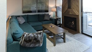A modern living room with a teal sofa, a coffee table, and a fireplace. - True Ski in Ski Out in Old Town. Newly Renovated. Walk To Main St. (Park City)