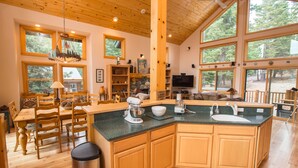 A spacious kitchen with wooden cabinetry, a central island, and large windows offering views of the outdoors. - Mountain Luxury Retreat for families & friends, new hot tub, 4 bedroom, 2.5 bath (Truckee)
