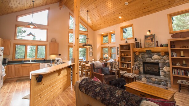 A spacious living area with a stone fireplace, wooden furniture, and large windows offering natural light. - Mountain Luxury Retreat for families & friends, new hot tub, 4 bedroom, 2.5 bath (Truckee)