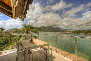 A wooden table and bench on a balcony with a metal railing, overlooking a body of water and mountains. - PRIVATE Ocean Front Cottage Over Looking  Beautiful Kalapaki Bay (Lihue)