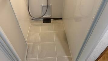 A small, enclosed shower area with tiled flooring and a showerhead.
