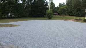 A gravel driveway leading to a house with a red roof, surrounded by trees and a grassy area. - Rider's Rest #1: Within 2 Miles Of Tryon International Equestrian Center (Rutherfordton)