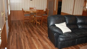 A room with a wooden dining table, chairs, a black leather sofa, and a clock on the wall. - Rider's Rest #1: Within 2 Miles Of Tryon International Equestrian Center (Rutherfordton)