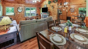 A cozy cabin interior with a dining area, sofa, and kitchen. - Amazing & beautiful with huge yard for kids to play with outdoor games, fire pit (Sevierville)