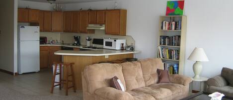 Una sala de estar con un sofá color beige, una mesa de centro y una estantería llena de libros.