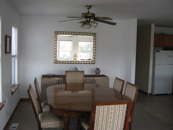 A dining room with a round table, chairs, a ceiling fan, a large mirror, and a refrigerator. - On the Water Oasis, 3 Bdrm, 2 Full Bath, and Walking Distance to Ventnor Beach (Ventnor City)