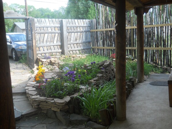 A garden with a stone wall, various plants, and a wooden fence. - Casita Rael, an Art lovers get-a-way (Taos)