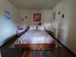 Une chambre à coucher avec un lit en bois, une table de chevet avec une lampe et une petite horloge murale.