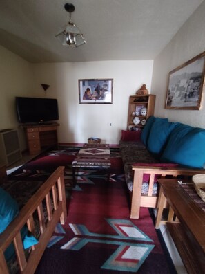 A living room with a television, sofa, coffee table, patterned rug, and a painting on the wall. - Casita Rael, an Art lovers get-a-way (Taos)