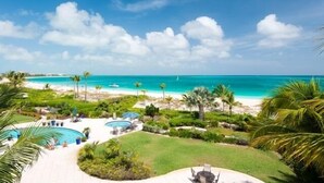 Een resort met een zwembad, palmbomen en uitzicht op het strand.
