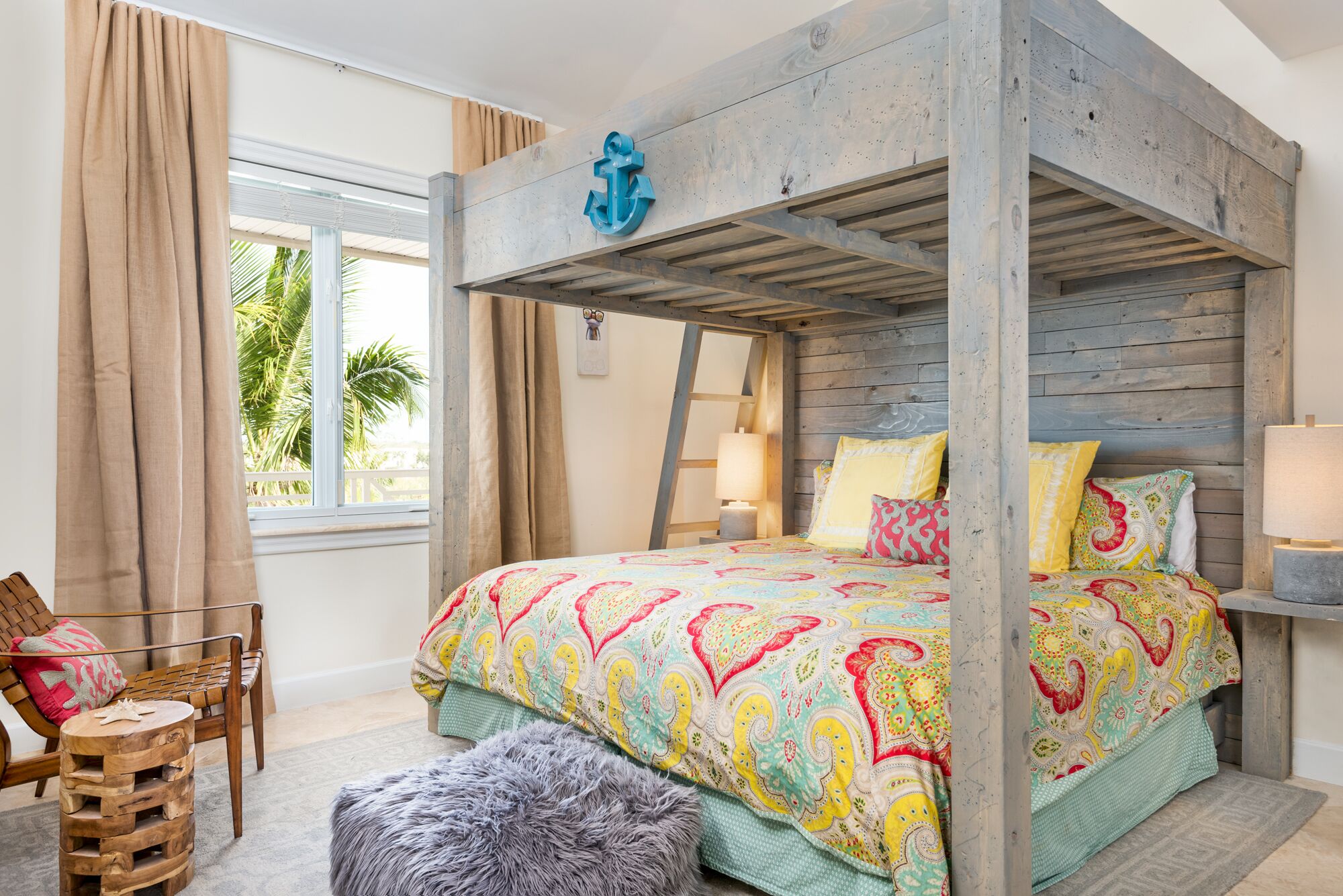 Ein Schlafzimmer mit Etagenbett, Holzboden, einem Fenster mit Vorhängen, einem Nachttisch mit Lampe und einer farbenfrohen Bettdecke.