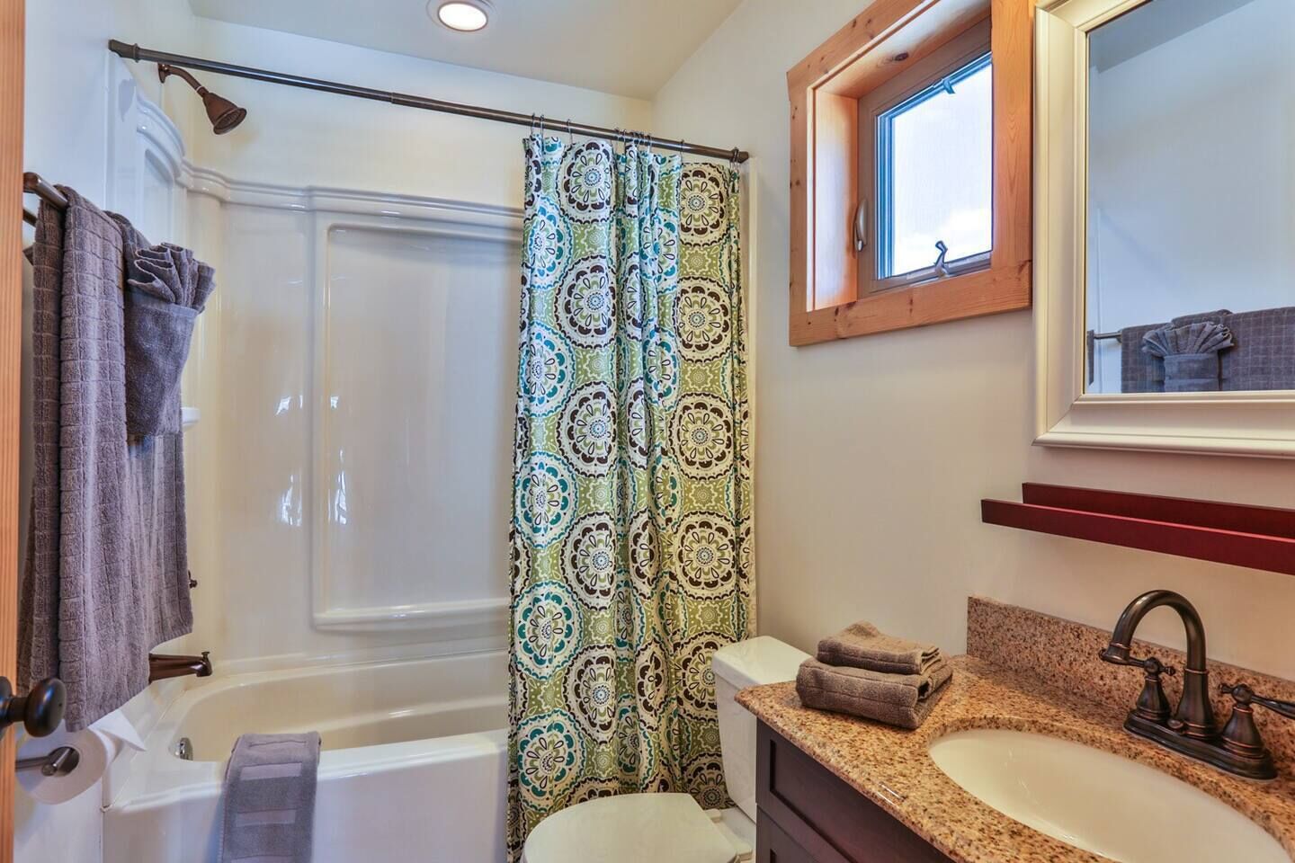 A bathroom with a shower, a sink, a mirror, and a window.