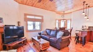 A cozy living room with a flat-screen TV, leather sofa, wooden coffee table, and a dining area with a wooden table and chairs. - Davis, WV 2BR full kitchen NR Stumptown Ales (Davis)