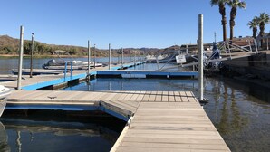 A marina with docked boats, a jet ski parking area, and palm trees in the background. - Private Marina, Docks, Close to Golf Course, Restaurants. (Parker)