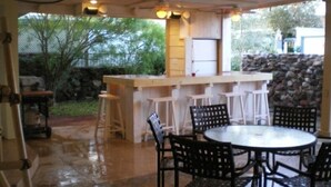 An outdoor kitchen area with a bar counter, stools, and a round table with chairs. - Private Marina, Docks, Close to Golf Course, Restaurants. (Parker)