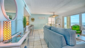 Un salón amplio con un sofá azul, un espejo redondo y una lámpara decorativa.
