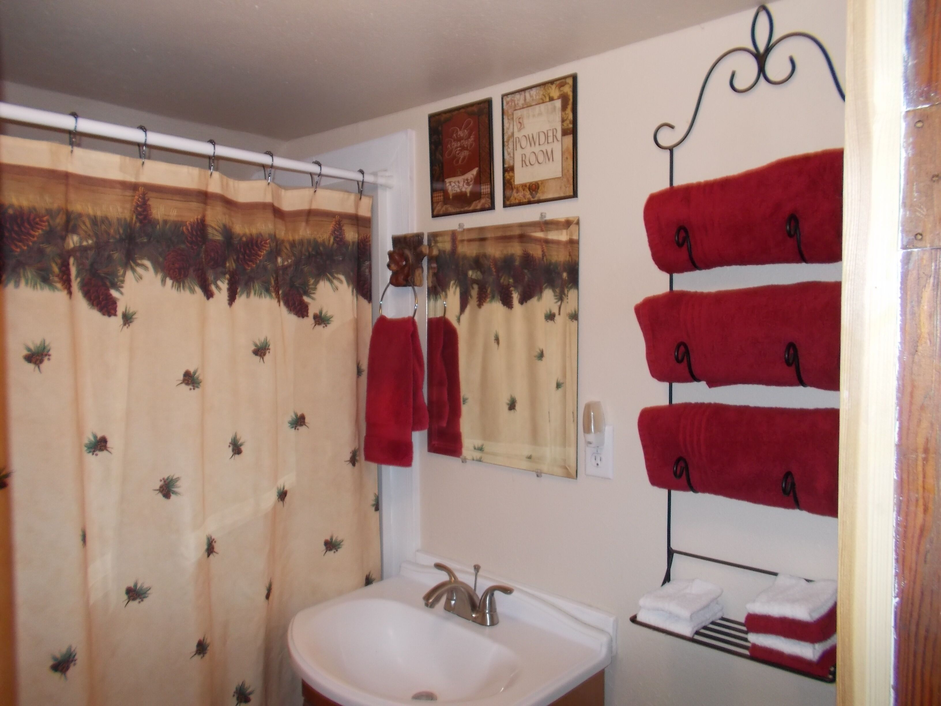 A bathroom with a shower curtain, a sink, a towel rack, and a sign indicating a powder room.