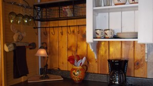 Une cuisine avec des meubles en bois, une machine à café et un luminaire suspendu.