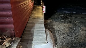 Une terrasse en bois menant à un bâtiment sur lequel est apposé un panneau indiquant « Stationnement interdit ».