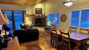 Un salon chaleureux avec une cheminée, un téléviseur et un coin repas agrémenté de meubles en bois.
