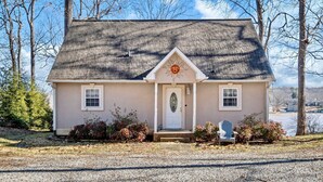 Une maison de plain-pied avec un toit à pignon, un porche à l’avant et un petit jardin.