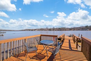 A wooden deck with a table and chairs overlooking a calm lake. - Lakefront/Boat Dock, 3/2, Furnished, Castaway Cottage, covered back deck views (Lexington)