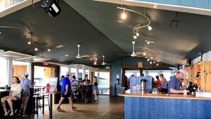 Un'ampia area interna con un bancone bar, pavimento in legno e diversi posti a sedere.