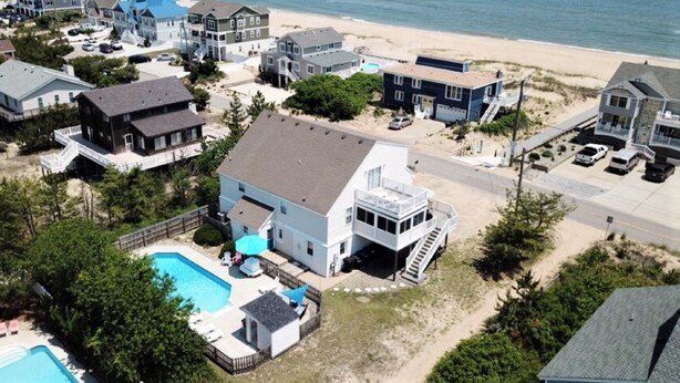 Una zona residenziale costiera con case, una piscina e una spiaggia sullo sfondo.