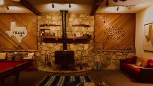 Una habitación acogedora con pared de piedra, un adhesivo mural con temática tejana, chimenea y mesa de billar.
