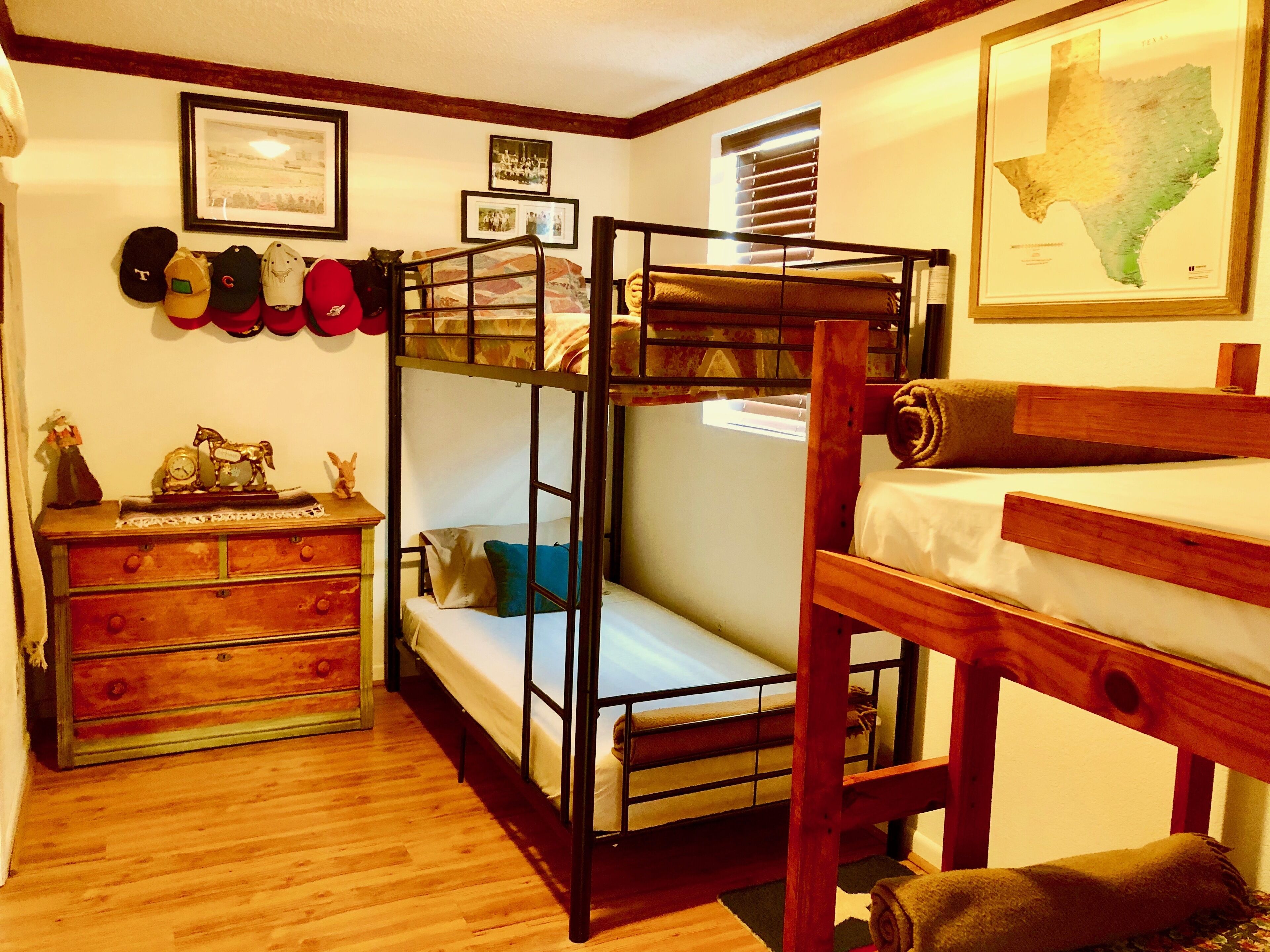Habitació amb literes, una petita estanteria, fotos emmarcades i un mapa penjat a la paret.