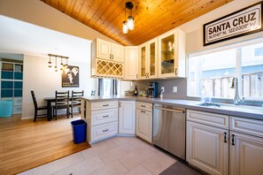 A modern kitchen with white cabinets, a stainless steel dishwasher, and a window with a view of the outside.