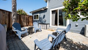 Eine Terrasse mit Gartenmöbeln, ein Holzzaun und ein Haus mit einer Schiebetür.