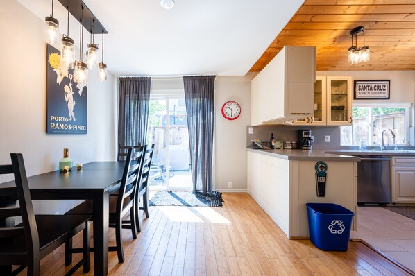 A modern kitchen with a dining area, wooden flooring, and a view to the outside.