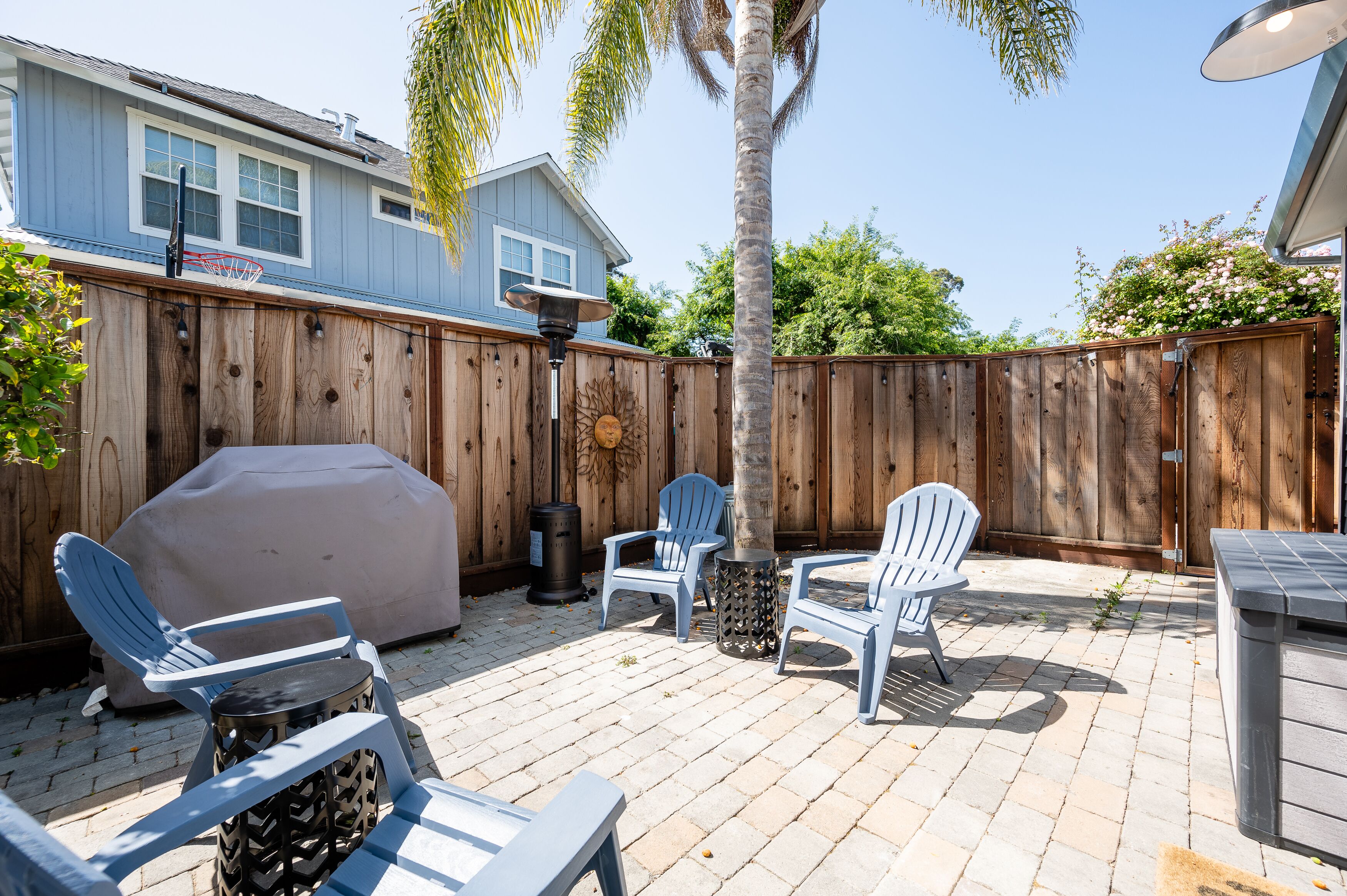 A backyard patio with outdoor furniture, a barbecue grill, and a wooden fence.