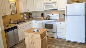 A kitchen with white cabinets, a stainless steel dishwasher, a microwave, an oven, and a refrigerator. - On Sunset Beach Island 1 Bedroom Condo sleeps 4 Water view! Unit 2 (Sunset Beach)