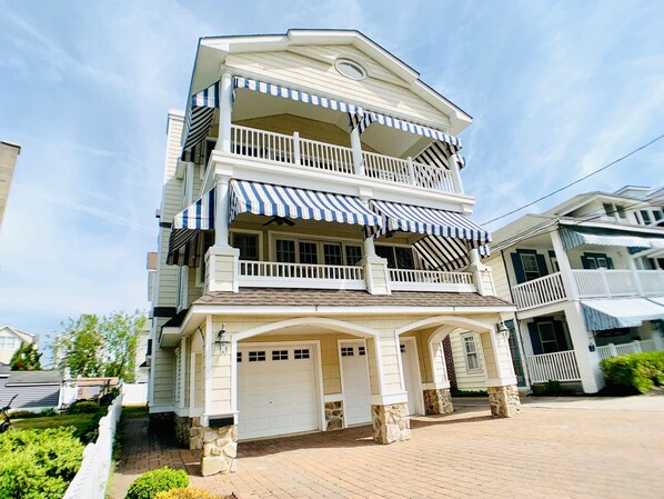 A multi-story residential building with a two-story balcony, a garage, and a stone foundation.