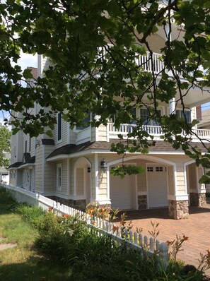 A two-story house with a covered porch, a stone foundation, and a white picket fence.