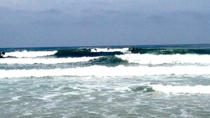 Een strand met golven en surfers.