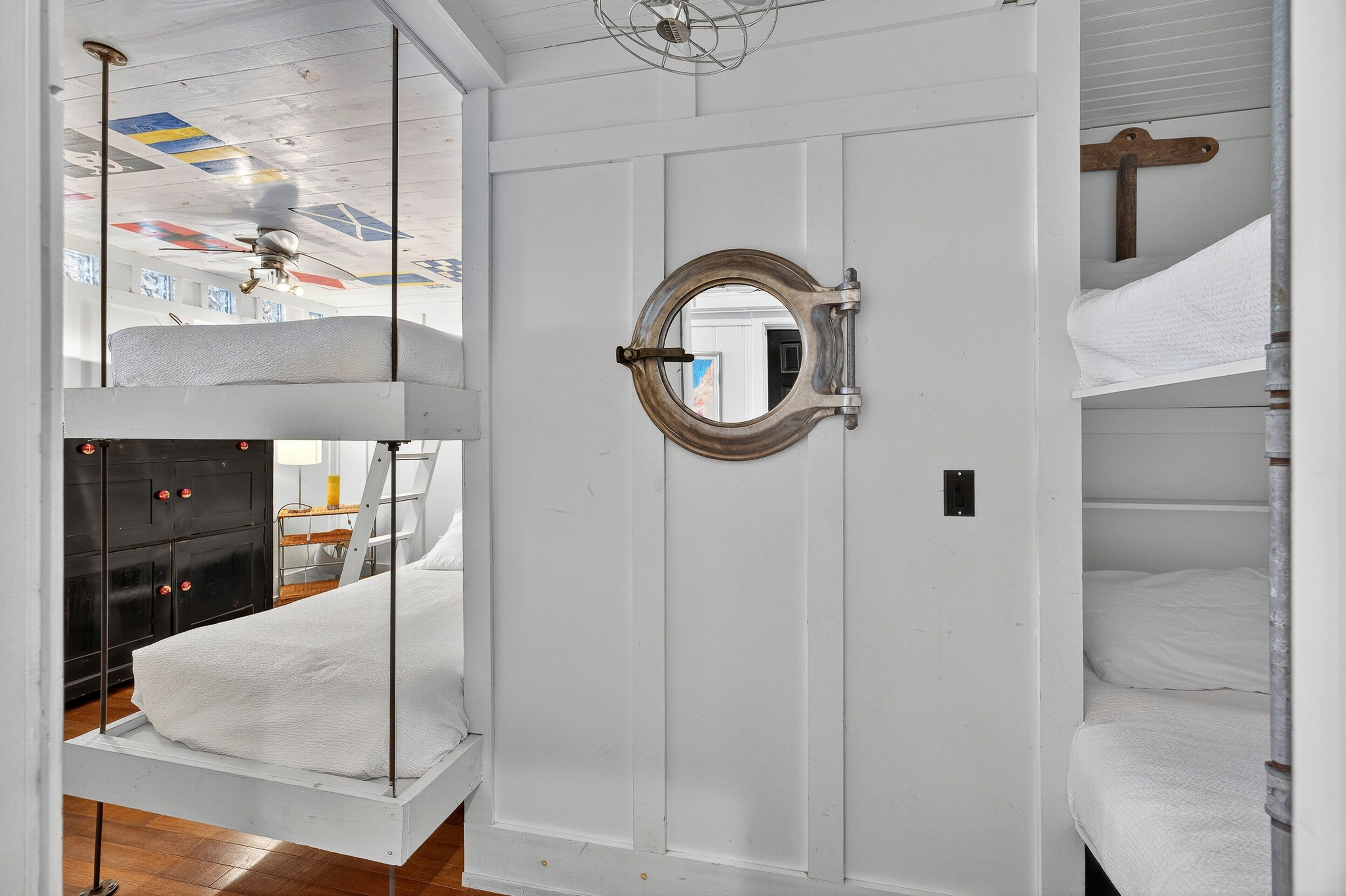Une pièce avec des lits superposés, une porte blanche et un ventilateur de plafond.