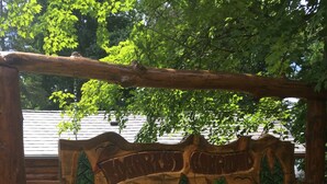 Een houten bord met een landschapsontwerp, geplaatst in een tuin met varens en rotsen.