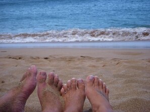 Een zandstrand met golven in de verte.